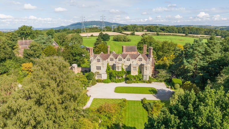 Aerial view, over trees, of the 16th-century mullioned manor house, Benthall Hall, Shropshire, and its surrounding parkland
